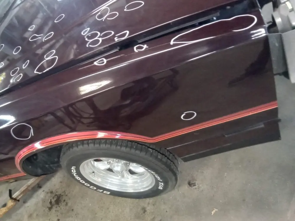 Dents on a maroon door and fender circled in white marker so each one is recorded.