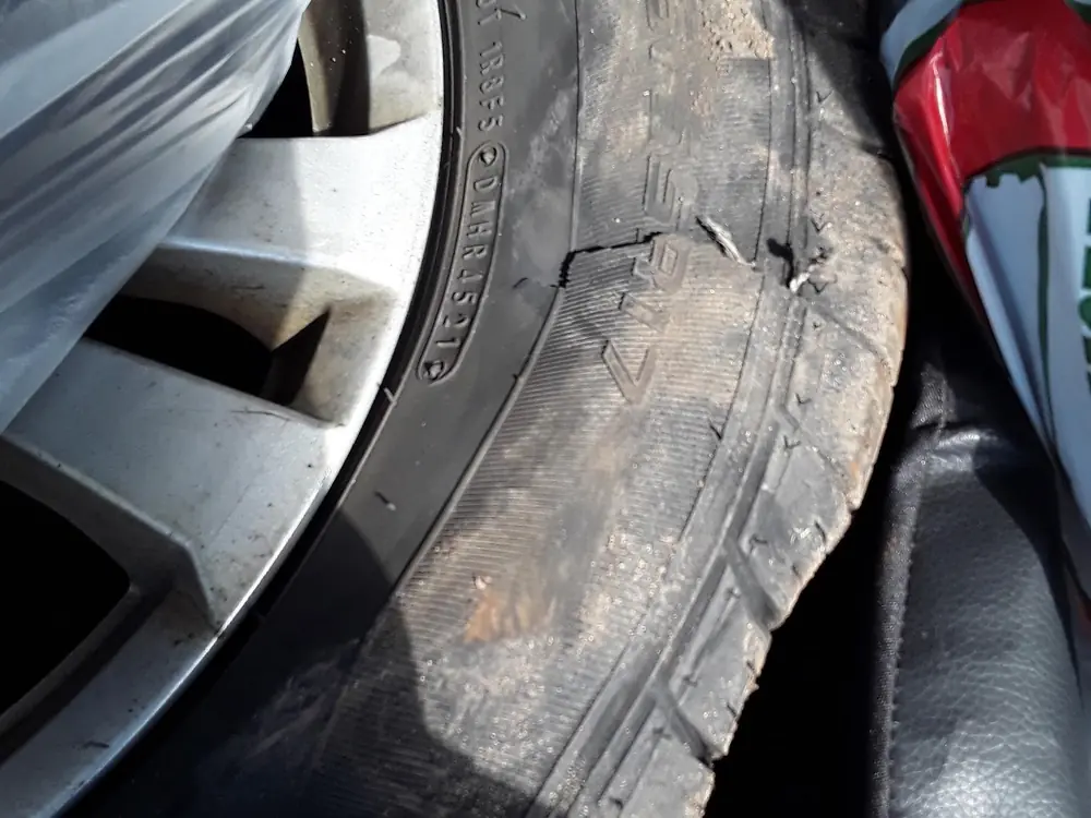 Close inspection of a tire with a cut, torn sidewall.