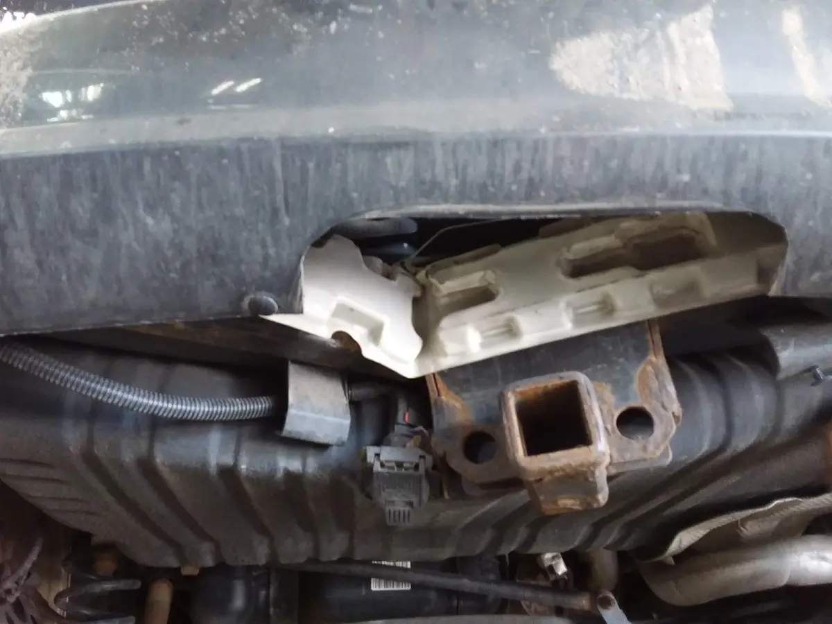 Underside of a vehicle on a lift, showing the frame and hitch area