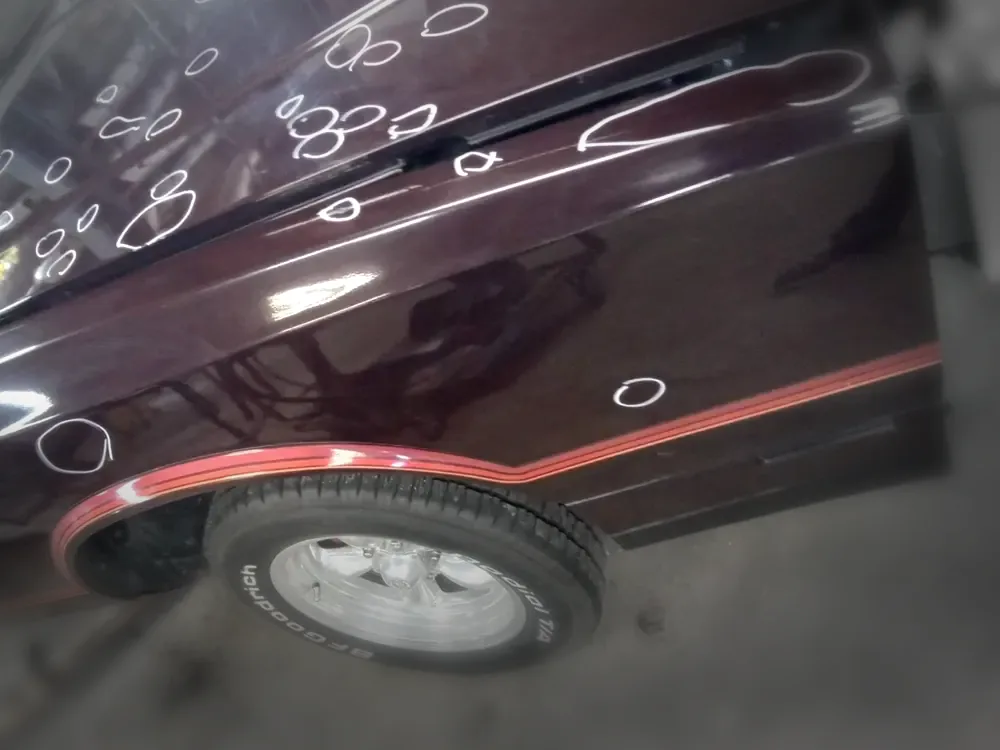 Dents on a maroon door circled for assessment